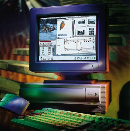An Acorn Risc PC 600 photographed in coloured studio lighting: a CRT monitor
                      showing the RISC OS desktop with several windows open, the two-slice system
                      case below it, and an Acorn keyboard and mouse in front.